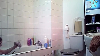 Brunette relaxes in bath and plays with her body